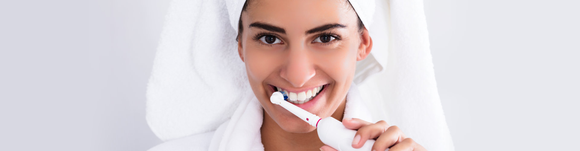 woman smiling while brushing her teeth