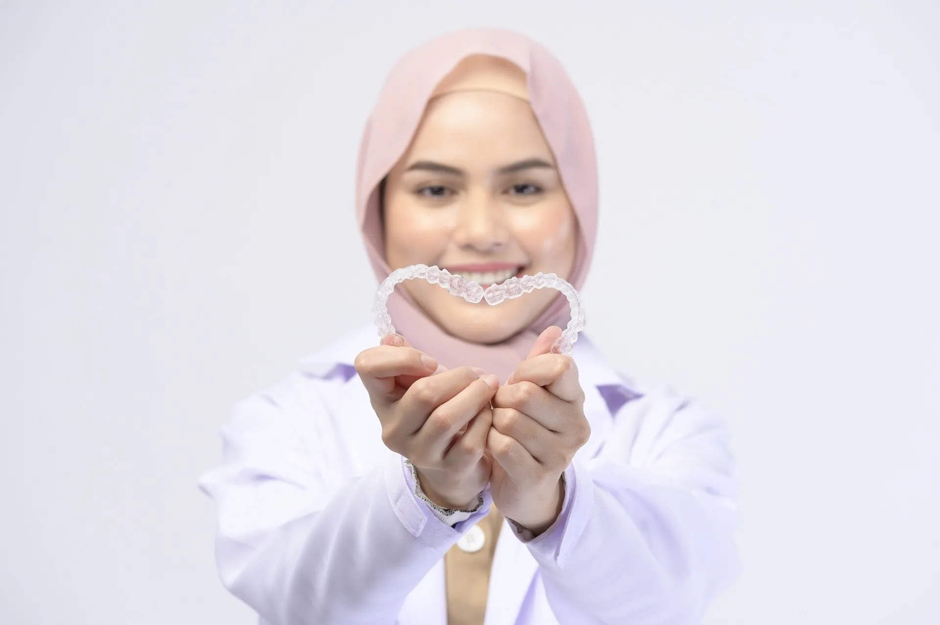 female dentist holding invisalign braces